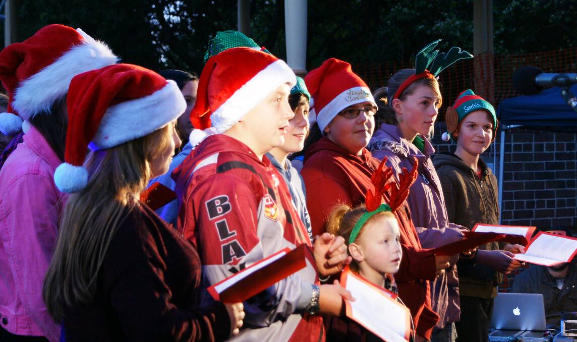 Songs of praise: Choristers during last year's Carols in Carrington may be praying for dry conditions this Friday evening.