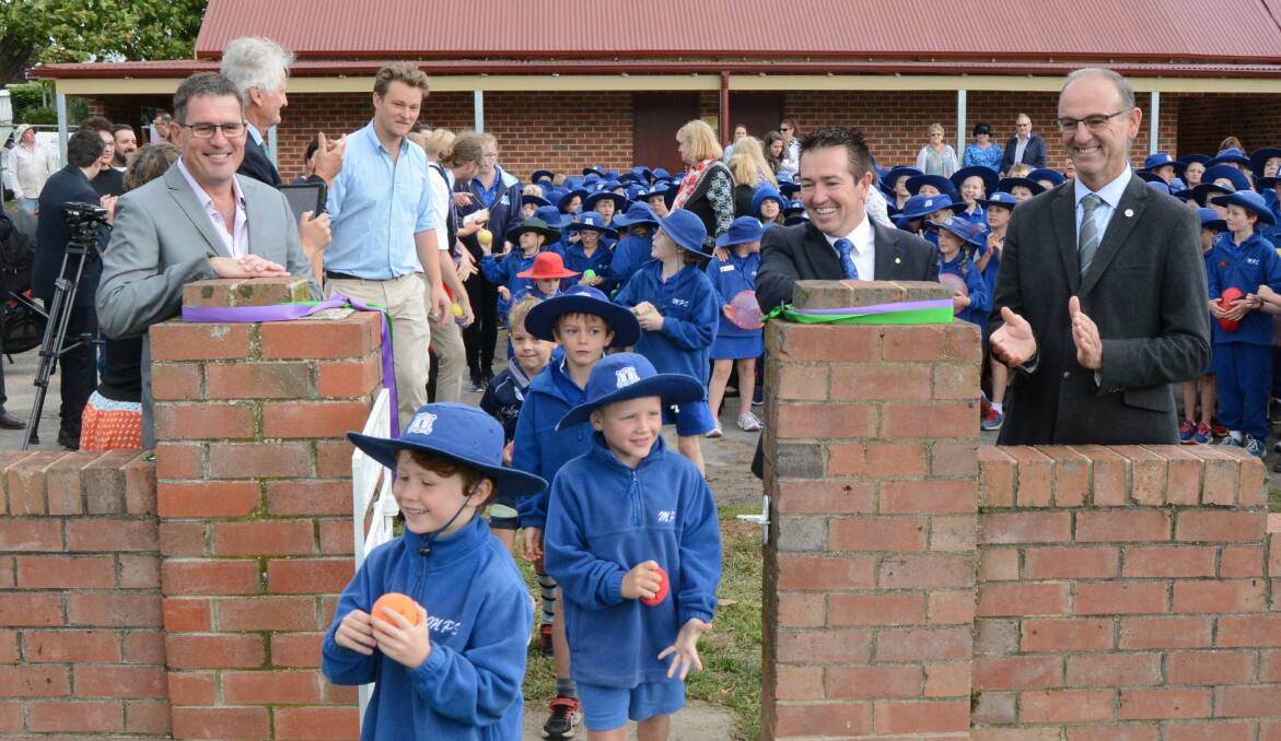 All smiles: Michael Truloff, Paul Toole and Scott Ferguson watch as Millthorpe Public School students teem onto the new Redmond Oval after the official re-opening. Photo: Mark Logan