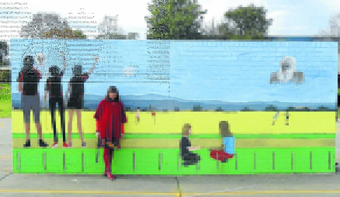 Nyree with a mural she painted at Cowra High School with students in the Breakaway program.