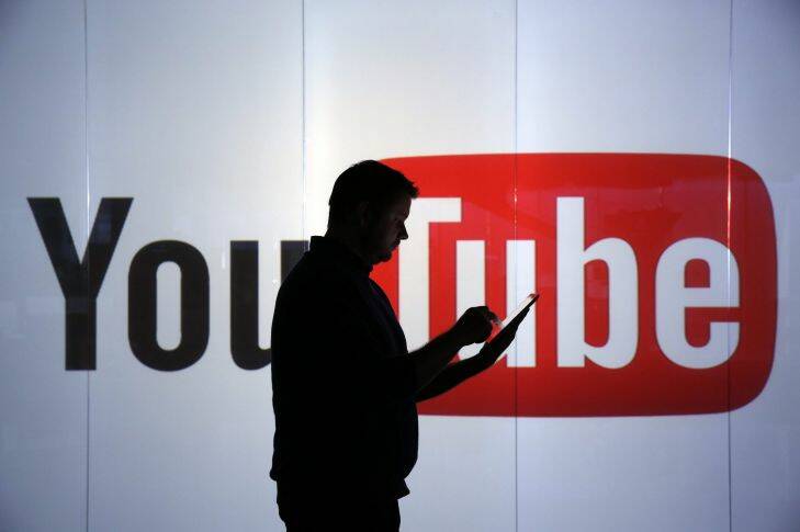 A man is seen as a silhouette as he checks a mobile device whilst standing against an illuminated wall bearing YouTube Inc.'s logo in this arranged photograph in London, U.K., on Tuesday, Jan. 5, 2016. YouTube Inc. provides consumer media and entertainment through its website. Photographer: Chris Ratcliffe/Bloomberg Photo: Chris Ratcliffe