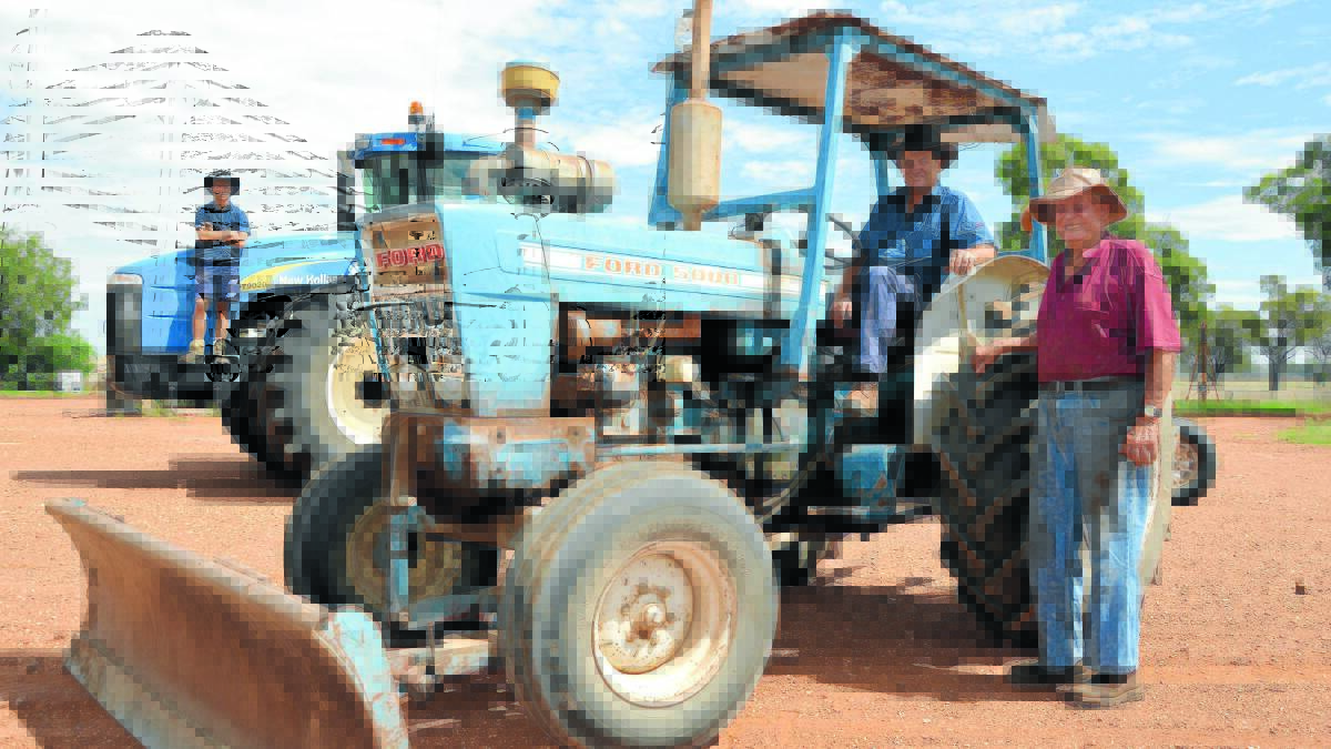 Neil and his dad Cliff with one of the property’s original tractors a Ford 5000 while in the background son Hayden is dwarfed by the modern New Holland. Photo: Bill Jayet 