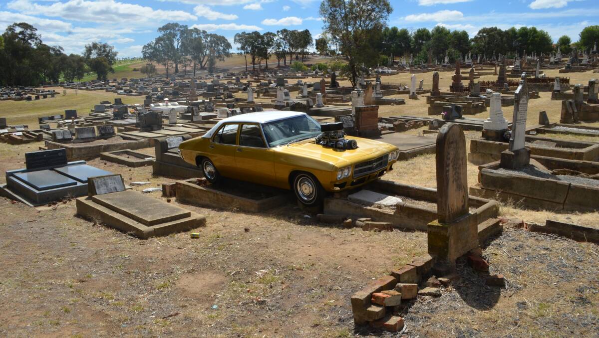 The gold HX Premier Kingswood Sedan that broke free of the tie-down points on its trailer and ended up on top of graves in Young's monumental cemetery. Photo: Edwina Mason, The Young Witness