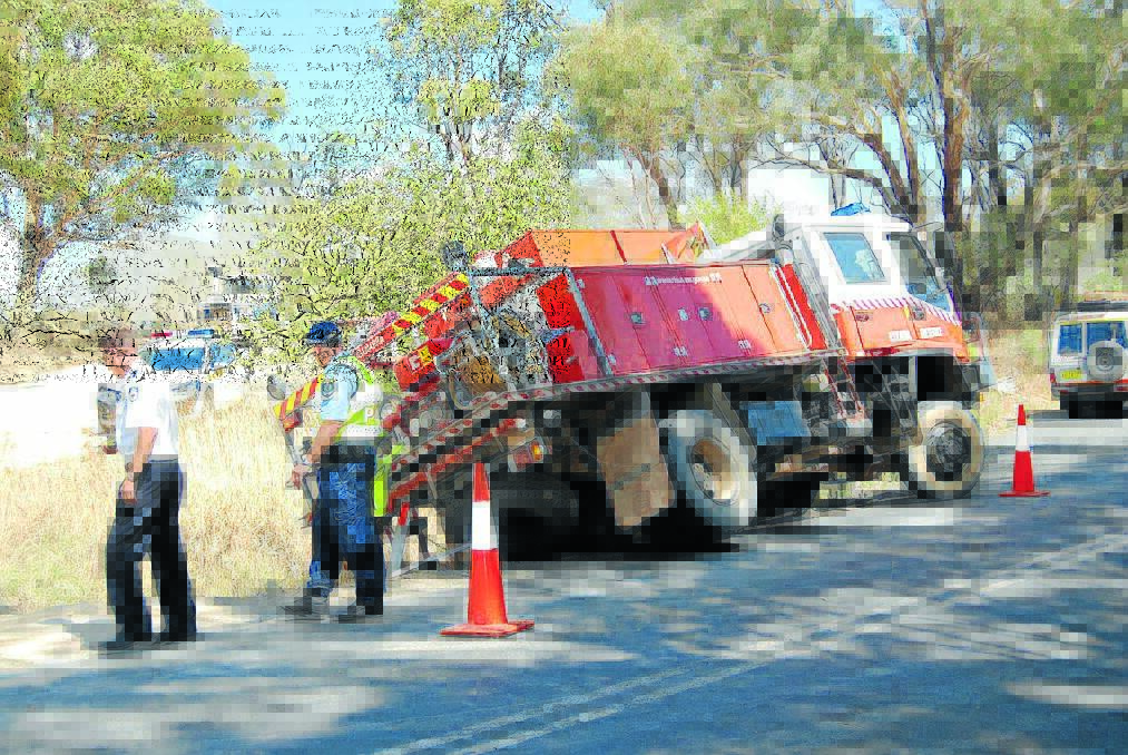 Police inspect the partially rolled RFS truck at Trunkey Creek yesterday.