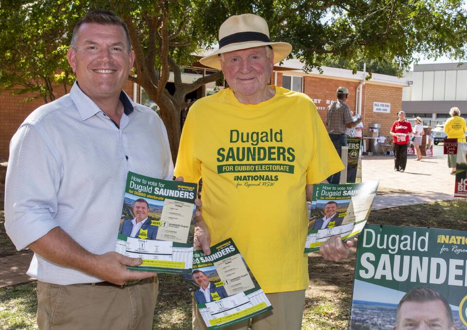 Dugald Saunders hands out 'how to vote' cards at the Dubbo Uniting Church pre-poll alongside his father. Picture by Belinda Soole 