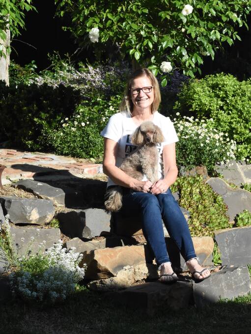 Small pleasures: Linda Oxley with her toy poodle Mia on the steps of their small courtyard garden. Photo: Mark Logan.