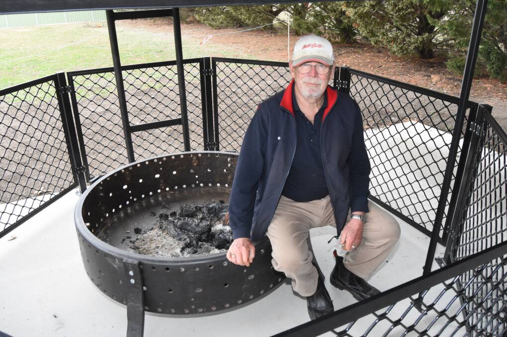 Hot seat: Graham Oliver with the new fire pit that's made from an old tractor wheel. Photo: Mark Logan.