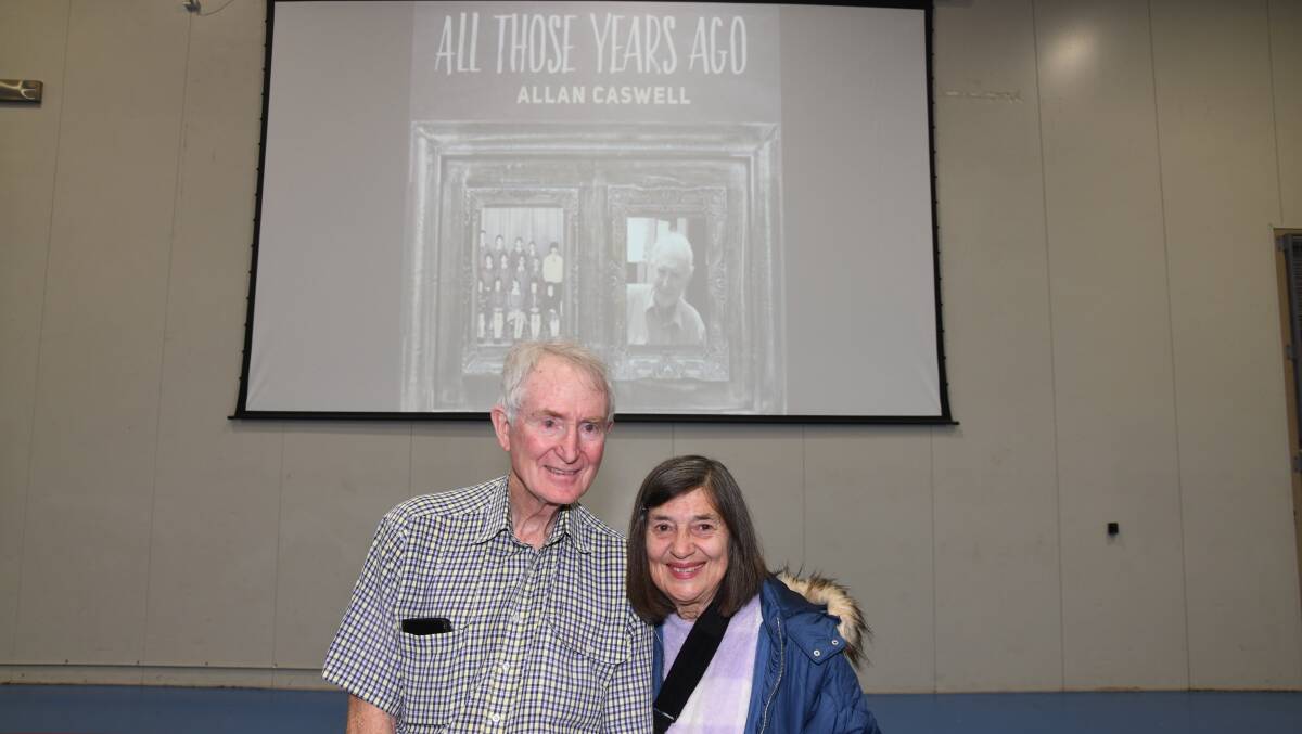 Retired James Sheahan Catholic High School teacher John Clarke, with wife Cathy Clarke beneath the cover of Allan Caswell's single, 'All Those Years Ago' which was written as a tribute to him. Picture by Carla Freedman
