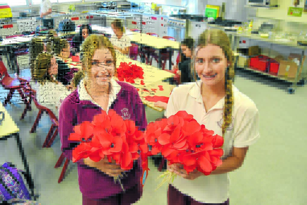 Blayney High School year 10 students Abby Connolly and Kate Redmond with some of the poppies that will form the backdrop to the school's Anzac Day service.